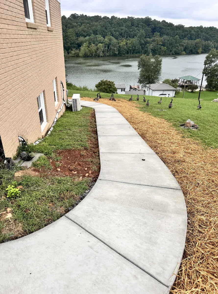 Sweeping curved concrete walkway following the grade beside a lakefront home in the NC Foothills &mdash; The Concord Concrete Company